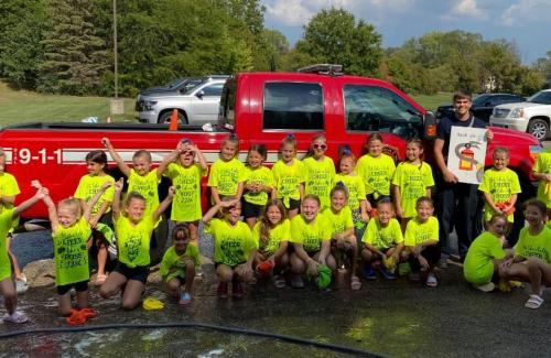 Group of children pose for their post car wash photo.  
