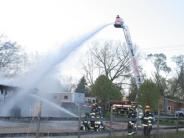 firemen and a crane spraying water on a burning building