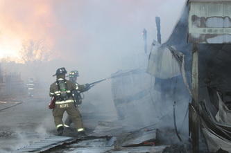 2 firemen spraying water on a fire