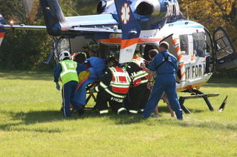 firemen and emts helping someone onto a helicopter to the hospital